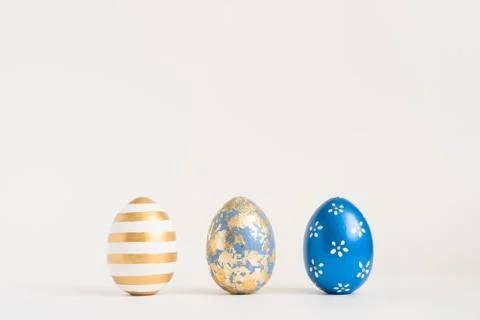 Three Easter golden decorated eggs on blue background. Minimal easter concept 스톡 사진
