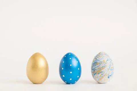 Three Easter golden decorated eggs on blue background. Minimal easter concept Stock Photos