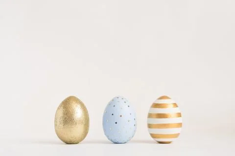 Three Easter golden decorated eggs on blue background. Minimal easter concept 스톡 사진