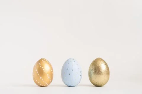 Three Easter golden decorated eggs on blue background. Minimal easter concept 스톡 사진