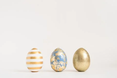 Three Easter golden decorated eggs on blue background. Minimal easter concept 스톡 사진