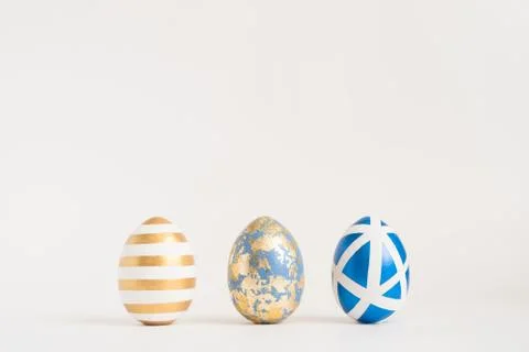 Three Easter golden decorated eggs on blue background. Minimal easter concept 스톡 사진