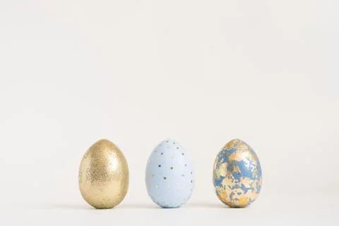 Three Easter golden decorated eggs on blue background. Minimal easter concept 스톡 사진