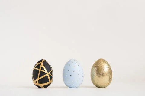 Three Easter golden decorated eggs on blue background. Minimal easter concept 스톡 사진