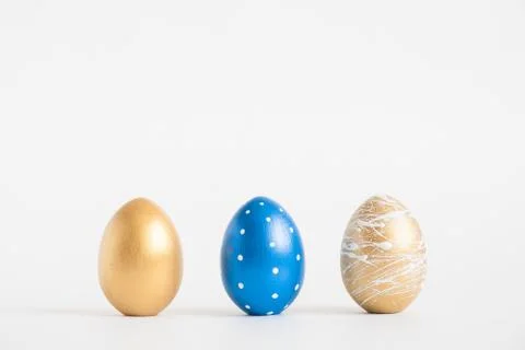 Three Easter golden decorated eggs on blue background. Minimal easter concept 스톡 사진