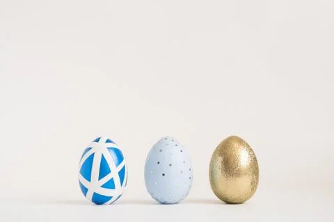 Three Easter golden decorated eggs on blue background. Minimal easter concept 스톡 사진