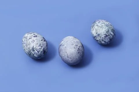 Three easter marbled purple eggs on blue background Stock Photos