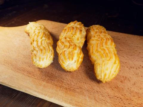 Three eclairs on a cutting board. Choux pastry. Stock Photos