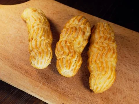 Three eclairs on a cutting board. Choux pastry. Foto stock