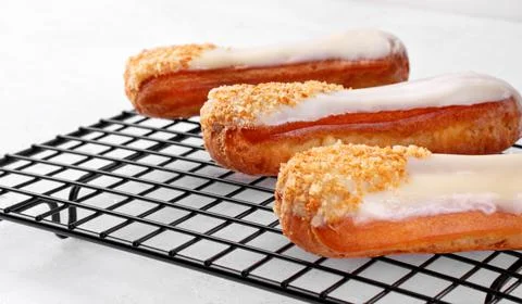 Three eclairs with white icing on the cooling rack Stock Photos