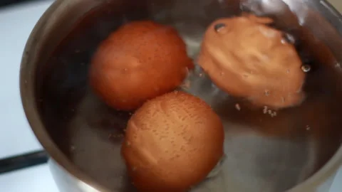 Three eggs are boiled in a saucepan in boiling water Video stock 265553813