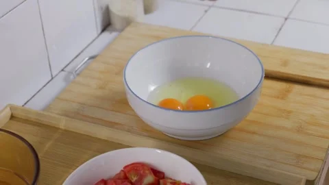 Three eggs are cracked into a bowl. Preparation before scrambled eggs. Stockbeeldmateriaal 341300481
