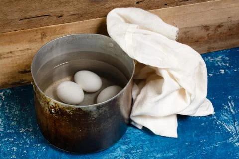 Three eggs boiling in dirty pan of water Stock Photos