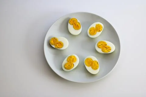 Three eggs cut to half each with two yolks on a plate Stock Photos