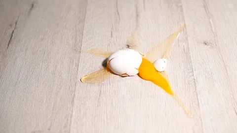 Three eggs fall to the floor and break. Yolk and protein slowly spread across Stock Footage 124324517