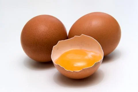 Three eggs, one broken egg, egg yolk, isolated on a white background Stock Photos