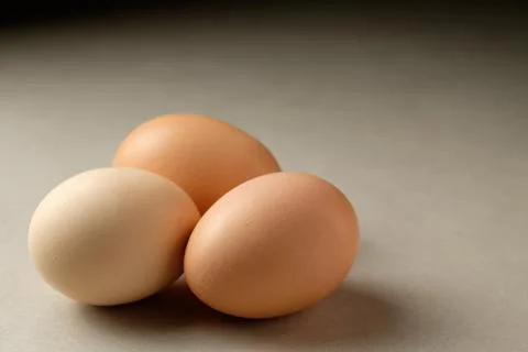 Three eggs resting peacefully on a smooth surface in soft light Stock Photos