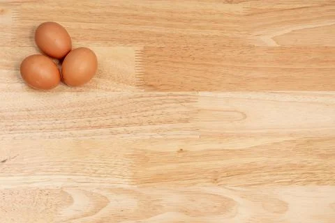 Three eggs on the upper left corner of the wooden table Stock Photos