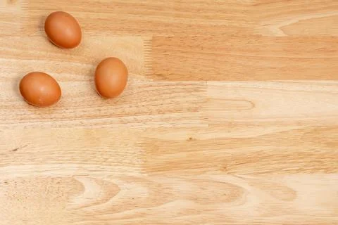 Three eggs on the upper left corner of the wooden table Stock Photos