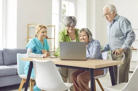 Three eldery patients learning to use notebook with supportive carer. Stock Photos
