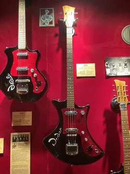 Three electric guitars on a red gradient background, varying designs and colo Stock Photos