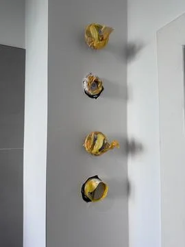 Three electrical junction boxes covered with yellow tape are mounted on a s.. 库存照片