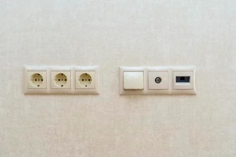 Three electrical outlets on the wall against a background of sand colored Wal Stock Photos