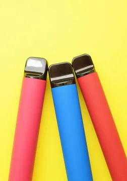 Three electronic cigarettes on a yellow background. Place for your text. Stock Photos