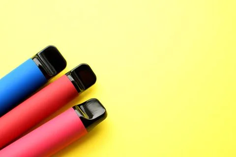 Three electronic cigarettes on a yellow background. Place for your text. Stock Photos