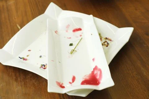 Three elegant white serving plates with remnants of food and colorful garnishes Stock Photos