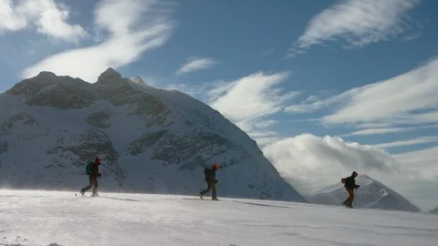 Three elite skiers walking on the snow covered mountains on a sunny day Stock Footage 116787005