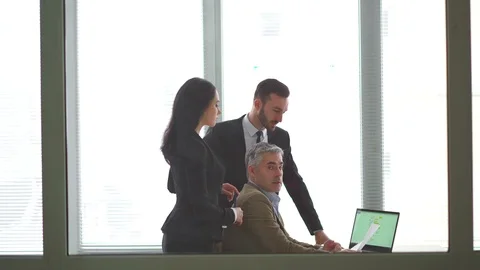 The three employees discussing at the table in the office room Stock Footage 105202114