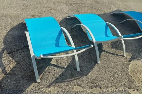 Three empty beach chairs made of metal and plastic on the asphalt pavilion Stock Photos