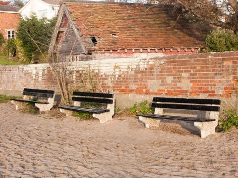 Three empty benches outside on beach near wall Stock Photos
