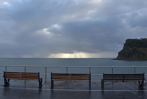 Three empty benches at sunride on a winters day in Teignmouth Devon. Stock Photos
