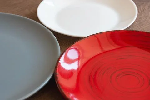 Three empty colorful plates on dark background vertical template. Stock Photos