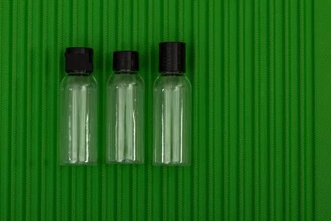 Three empty cosmetic containers placed on a green suitcase, the permitted c.. Stock Photos