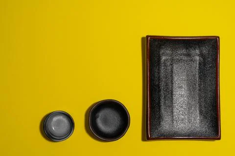Three empty dark plates on yellow background Stock Photos