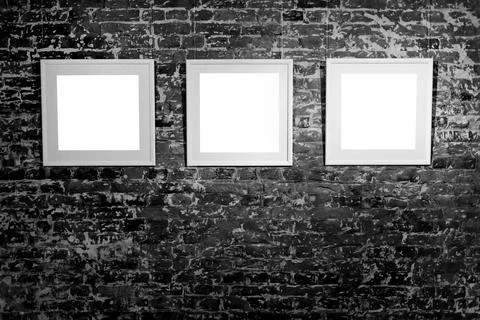 Three empty frames on black brick wall. Blank space posters or art frame wait Stock Photos