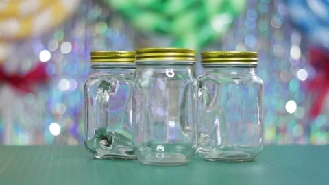 Three empty glass jars in close up on table with shiny festive background Stock Footage 274485987