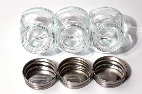 Three empty glass jars with scattered lids. Isolate Stock Photos