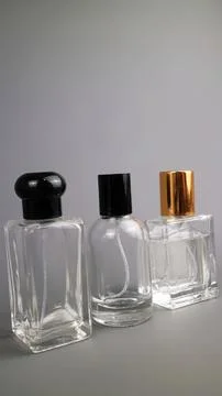 Three empty glass perfume bottles with different caps on gray background Stock Photos
