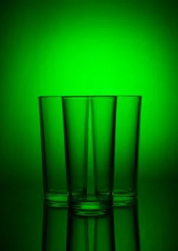 Three empty glasses on green background with reflection Stock Photos