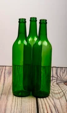 Three empty green glass wine bottles on a wooden table. Stock Photos