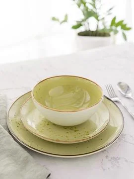 Three empty green plates with silver cutlery and tablecloth on white marble Stock Photos