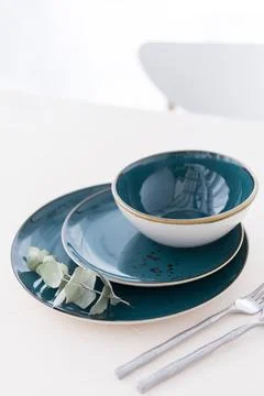 Three empty green plates with silver cutlery on white table in front of window Stock Photos