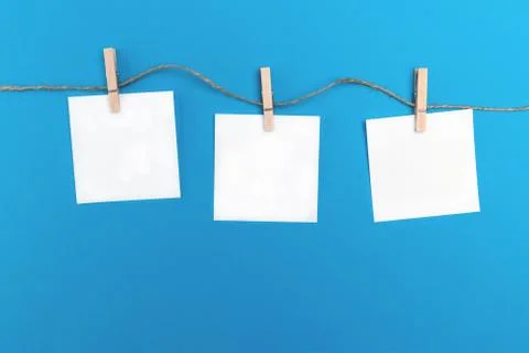 Three empty little sheets of paper hold by wooden clothespins on a string. Cr Stock-Fotos