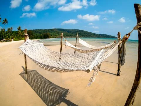 Three empty rope cradle hanging on the wooden poles on sandy beach on the s.. Stock Photos