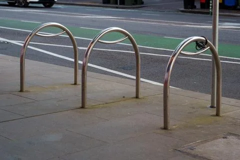Three empty silver metal bicycle racks stand prominently on a grey paved si.. Stock Photos