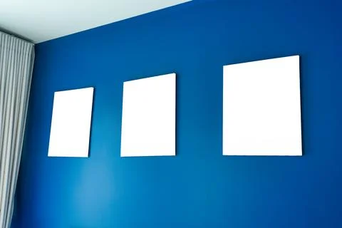 Three empty square canvas frames arranged on deep blue wall Stock Photos